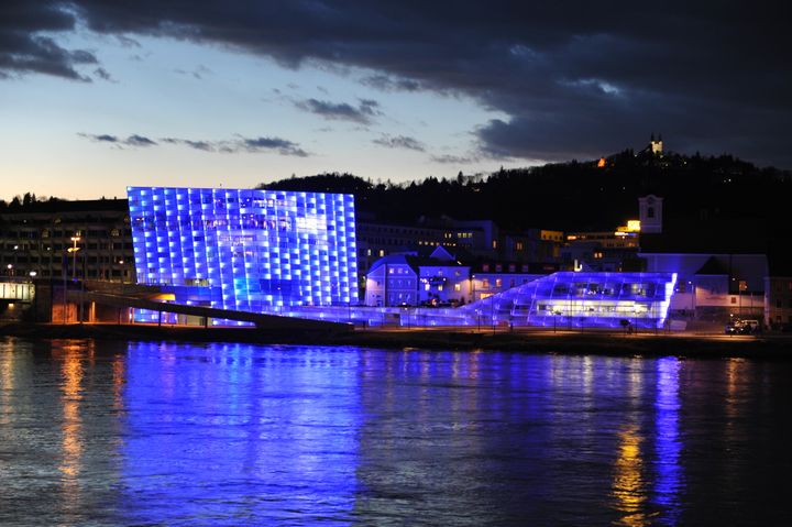 Das blau beleuchtete Ars Electronica Center an der Donau bei Nacht
